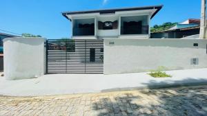a white house with a gate and a brick driveway at Studio 209-AP2 espaço completo ideal para casal in Ubatuba