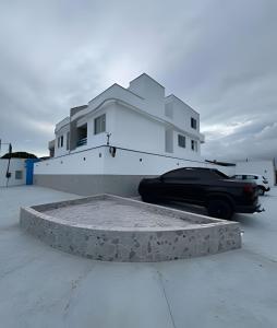 a black car parked in front of a white house at Flats com Temática Grega na Praia de Aruana | Atena Flats in Aracaju