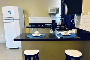 a kitchen with two stools with hats on a counter at Flats com Temática Grega na Praia de Aruana | Atena Flats in Aracaju