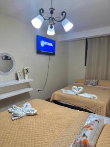 two beds in a room with a tv on the wall at Galicia Lodgement in Lima