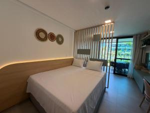 a bedroom with a bed and a large window at Flat Premium Muro Alto-conforto a 150m do mar in Ipojuca +28 photos
