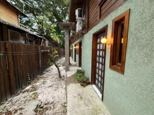 a house with a fence next to a street at Vilarejo hospedagem- Espaço Beco Carioca in Ilha do Mel
