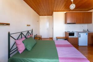 ein Schlafzimmer mit einem grünen Bett und rosa und grünen Kissen in der Unterkunft Hotel Patrai in Lefkada Town