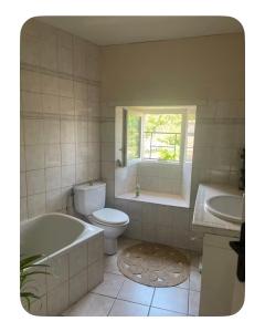 a bathroom with a tub and a toilet and a sink at Chambre dans Maison de campagne in Barbaste