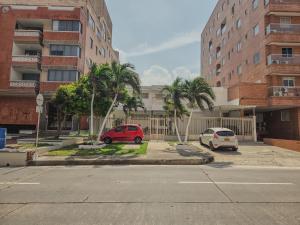two cars parked in a parking lot in front of a building at Margarita 93 in Barranquilla