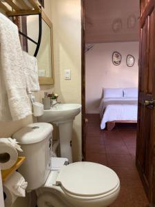 a bathroom with a toilet and a sink and a bed at Magic Lodge - Cirrí, Naranjo in Cirrí +15 photos
