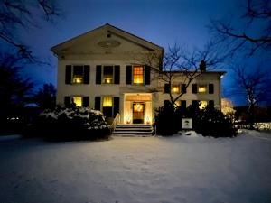 a white house with lights in the snow at night at Oak & Anchor Inn in Penn Yan