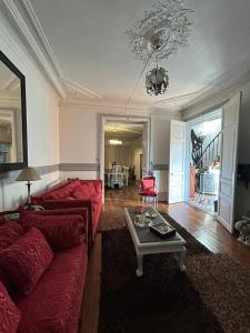 a living room with a red couch and a table at Maison Charmante in Vervins