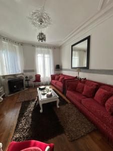 a living room with a red couch and a table at Maison Charmante in Vervins +12 photos
