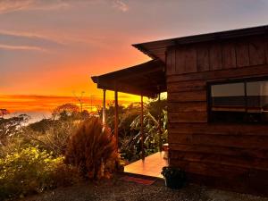 a wooden cabin with a sunset in the background at Magic Lodge - Cirrí, Naranjo in Cirrí