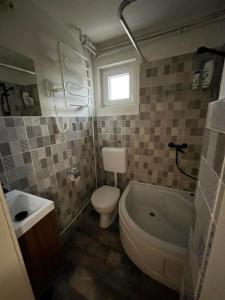 a bathroom with a toilet and a tub and a sink at Non stop apartman in Kaposvár +23 photos