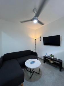 a living room with a black couch and a tv at Bijoc 01 Apartment in San Felipe de Puerto Plata