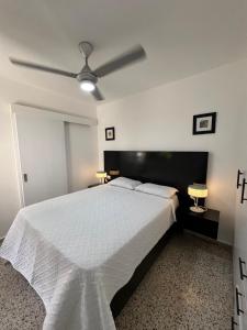 a bedroom with a white bed with a ceiling fan at Bijoc 01 Apartment in San Felipe de Puerto Plata