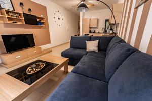 a living room with a blue couch and a tv at Cobalt Canopy a Spacious 2 Bedroom Apartment in St. Paul's Bay
