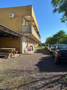 a building with cars parked in a parking lot at Pousada Mar & Sol in Torres