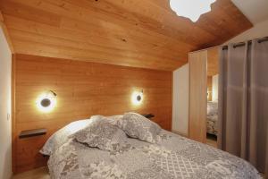 a bedroom with a bed with wooden walls and a ceiling at Gîte les Lilas Blancs 15mn Gérardmer in Champdray +58 photos