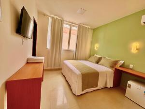 ein kleines Schlafzimmer mit Bett und Fernseher in der Unterkunft Mart's Hotel in Salvador