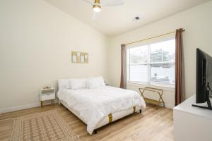 a white bedroom with a bed and a tv at Casa Del Café in Bluffton