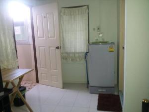 a kitchen with a refrigerator next to a door at Chomhaad Guesthouse in Hua Hin