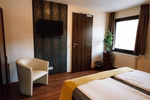 a bedroom with a bed and a chair and a television at Gasthaus SEPP in Dernau