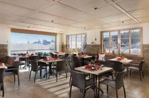 una sala da pranzo con tavoli, sedie e finestre di Bödele Alpenhotel a Schwarzenberg im Bregenzerwald