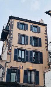 a tall building with black shutters on it at La Tour Grégoire in Clermont-Ferrand