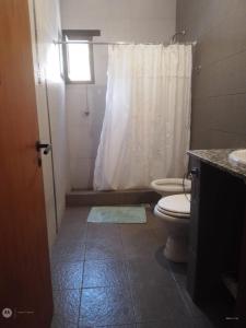 a bathroom with a toilet and a white shower curtain at Casa Verdes del Malka in Tilcara +4 photos