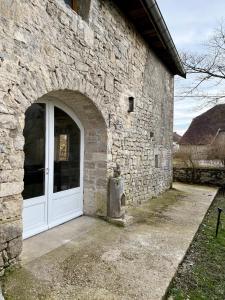 a stone building with a white door in front at Gîte 2 suites proche du lac de Chalain in Montigny-sur-lʼAin