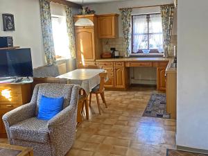a kitchen with a table and a blue pillow on a chair at Bauernhof Daurerhof Ferienwohnung in Aschau im Chiemgau +6 photos