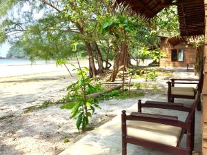 two benches sitting on a beach next to a building at La Ong Lay in Ko Phayam
