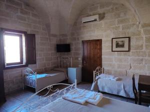 a room with two beds and a tv in a building at Tenuta Pigliano Hotel in Bagnolo del Salento