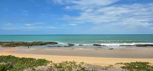 a sandy beach with rocks in the ocean at Vila Ohana Beira Mar - Caraíva in Caraíva