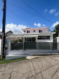 a pink house with a fence in front of it at Appartement vue mer Chez Ti Louis - Grande Anse in Les Anses-dʼArlets
