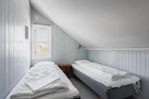 two beds in a small room with a window at Skottinden Panorama Lofoten in Ballstad