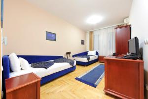 a living room with a blue couch and a tv at Hotel Dragović Smederevo in Smederevo