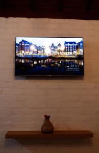a television on a wall with a vase on a shelf at Chalé Recanto da Paciência in Camanducaia