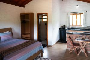 a bedroom with a bed and a desk and a table at Chalé Recanto da Paciência in Camanducaia