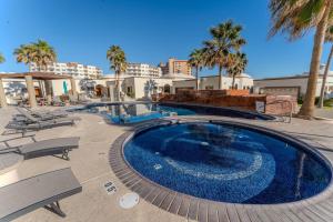 a large swimming pool with chairs and palm trees at Las Palmas Resort in Puerto Peñasco