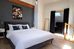 a bedroom with a large bed with white sheets at Le cocon d Épinal in Épinal