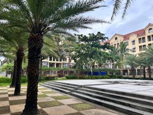 two palm trees in a park with buildings in the background at CJ Premier Stays at Amalfi Oasis Near SM Seaside Mall & Nustar Casino Hotel, Cebu City in Cebu City