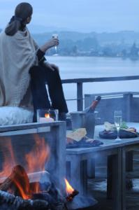 a woman sitting over a fire with a glass of wine at Hotel Patagonico in Puerto Varas +52 photos