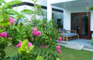 einen Garten mit rosa Blumen vor einem Haus in der Unterkunft Vina Beach Pool Villas in Hoi An