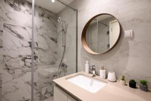 a bathroom with a sink and a shower with a mirror at inJoy in Sajmište +4 photos