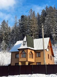 a wooden house with a snow covered roof at Котедж "У Мадяра" in Mykulychyn