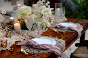 a wooden table with plates and candles and flowers at Alquimia Hotel Boutique in Tulum +204 photos