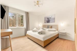 a white bedroom with a bed and a window at Lake Lodge Ossiacher See in Annenheim