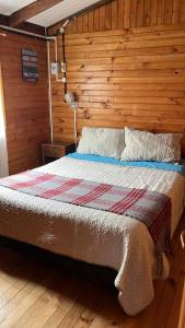 a bedroom with a bed with a wooden wall at Atardecer Inolvidable in Tomé