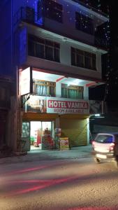 a building with a sign on the side of it at Hotel Vamika in Manāli