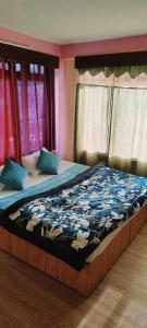 a bedroom with a large bed with blue sheets at Hotel Vamika in Manāli +3 photos