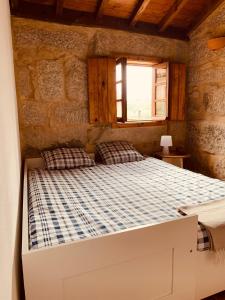 a bedroom with a bed in a stone wall at Refúgio da Póvoa Dão in Silgueiros